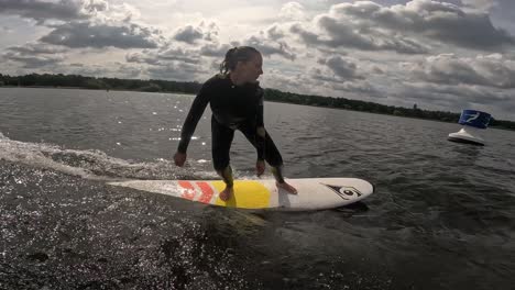 Mädchen-Surft-Wellen-Auf-Einem-Longboard-Hinter-Einem-Boot-Mit-Vielen-Wolken-Am-Himmel-Mit-GoPro-60fps