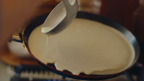 Close-up-of-pancake-batter-being-carefully-poured-into-a-hot-pan-and-distributed