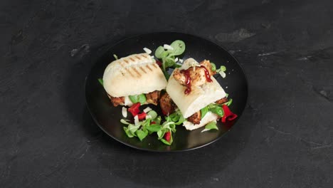 A-sandwich-bread-with-paprika,-salad-and-meat-is-presented-on-a-spinning-plate-