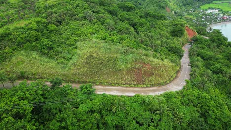 White-delivery-truck-drives-through-rainforest-jungle-in-the-Philippines,-drone