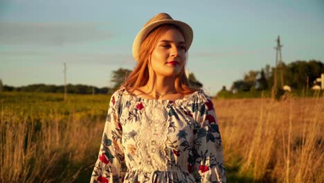 Stunning-HD-footage-of-a-beautiful-young-woman-in-a-dress,-wearing-a-knitted-hat-and-red-lipstick,-joyfully-walking-through-a-wheat-field