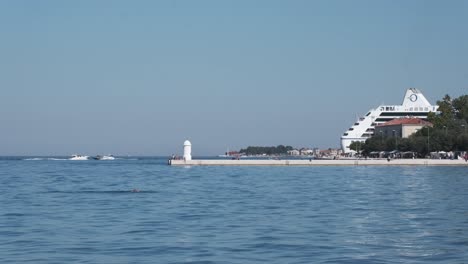 Wide-panorama-over-Zadar-promenade,-beacon-and-large-cruise-ship-docked-the-old-town