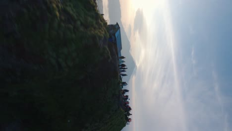 Aerial-drone-FPV-shot-of-crowd-of-tourists-on-the-top-of-mount-Batur-in-Bali,-Indonesia-with-sun-rising-in-the-background