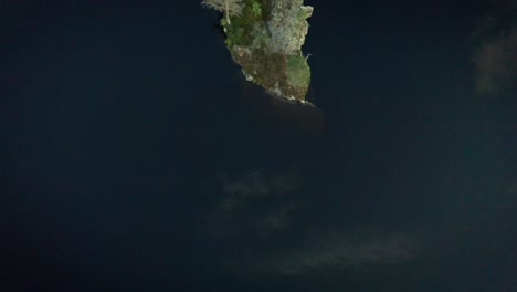 Top-down-aerial-over-thin-lake-island-with-trees-in-remote-Norway