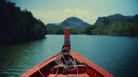Sitting-in-the-front-of-a-red-long-tailed-boat-while-sailing-down-a-river-in-Thailand