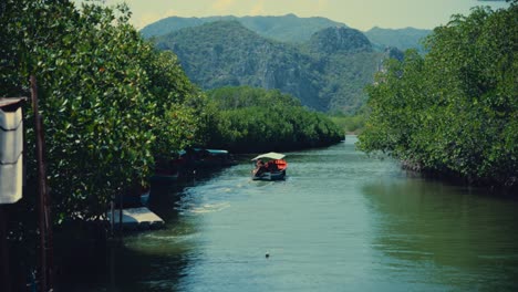 A-long-tailed-boat-sails-out-into-a-river-in-a-Thai-National-Park