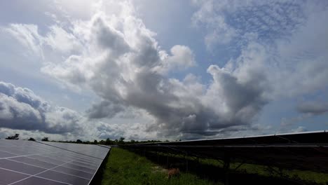 Revelando-Conjuntos-De-Paneles-Solares-Contra-El-Fondo-Del-Sol-Y-Las-Nubes-En-La-Planta-De-Energía-Renovable-De-Jambur,-Gambia---África
