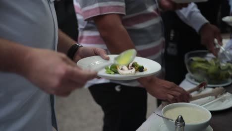 Slow-motion-shot-of-a-group-of-people-dressing-their-plates-of-food-with-a-garnish