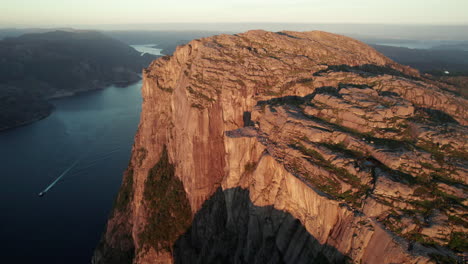 Stunning-Aerial-View-of-an-impressive-Cliff-in-Norway,-Sunrise-Atmosphere-in-the-Lysefjorden,-Preikestolen,-Drone-Rotating-around-the-Pulpit-Rock-with-Some-Tourists