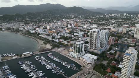 Santa-Marta,-Kolumbien,-Blick-Auf-Den-Hafen-Mit-Segelboot-Und-Hotelgebäude-Wolkenkratzer-Luftaufnahmen
