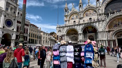 Street-Stall-In-St-Marks-Square-Selling-Touristy-T-Shirts-In-Front-Of-Saint-Marks-Basilica-And-St-Mark's-Clocktower-In-Venice
