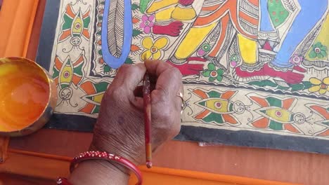 close-up-scene-in-which-a-woman-artist-is-painting-a-painting-of-Madhubani