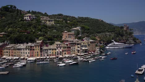 Picturesque-bird's-eye-view-of-the-waterfront-promenade-is-cafes,-restaurants,-boutiques,-vibrant-houses-and-boats-in-the-harbour-of-Portofino,-Italy