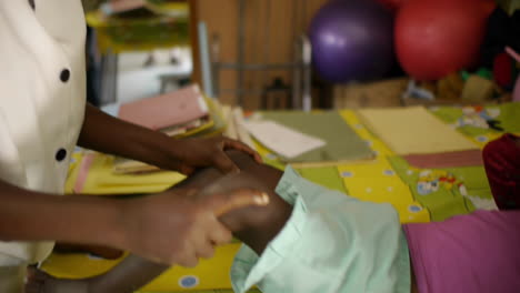 Afrikanerin-Hilft-Bei-Der-Beweglichkeit-Der-Kinderbeine-Auf-Dem-Patiententisch