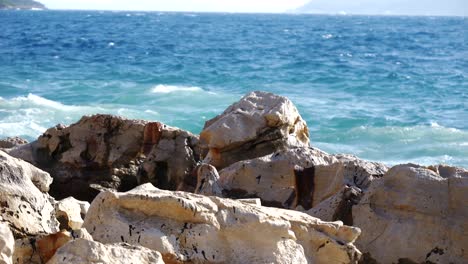 Close-up-of-foamy-waves-of-the-Adriatic-Sea-crashing-against-the-rocky-shore-of-an-Albanian-beach