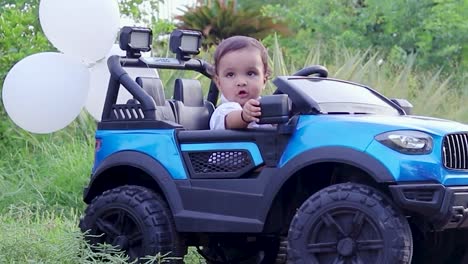 isolated-cute-baby-boy-toddler-sitting-in-toy-car-and-adjusting-the-mirror-at-outdoor