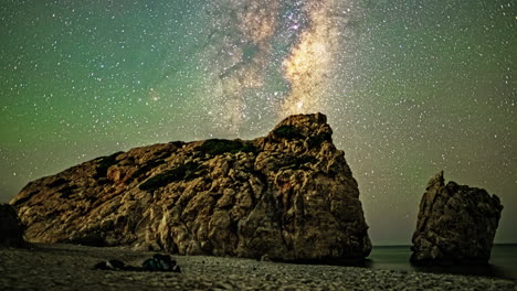 Timelapse-Captures-a-Man-Lying-on-the-Beach,-Gazing-at-the-Night-Sky-Beside-a-Vast-Boulder
