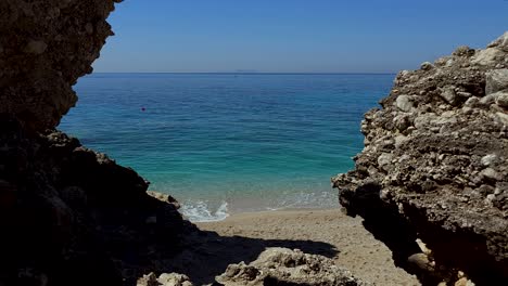 Peaceful-seaside-with-blue-turquoise-sea-seen-through-cliffs-and-sand-beach,-beautiful-spot-for-summer-holiday-in-Mediterranean