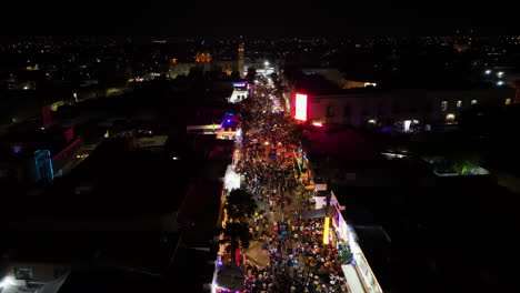 Flying-over-people-at-the-Feria-San-Marcos-Aguascalientes-event,-night-in-Mexico---Aerial-view
