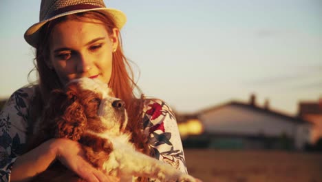 Stunning-HD-footage-of-a-white-Caucasion-girl-with-a-knitted-hat-and-red-lipstick-holding-a-dog-Cavalier-King-Charles-Spaniel-in-her-arms,-hugging-and-caressing-it