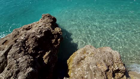 Von-Kristallklarem-Meerwasser-Umspülte-Klippen-An-Einem-Felsigen-Strand-Mit-Sand-Bei-Sonnenaufgang-Im-Mittelmeer,-Schöne-Sommerferien