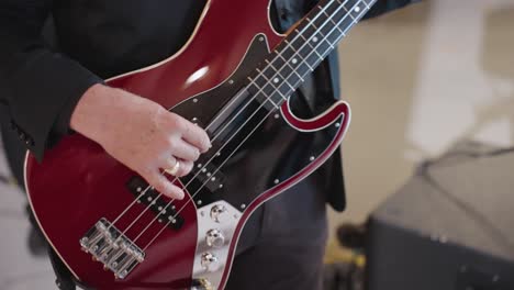 White-Man's-Hand-Strumming-Red-Electric-Bass-Guitar-Close-Up