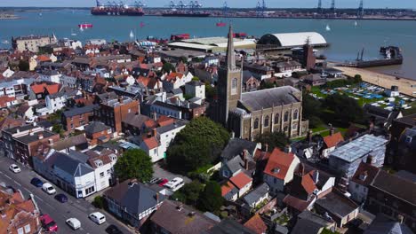 Drone-view-flying-over-town-and-church-in-Harwich,-heading-towards-harbour