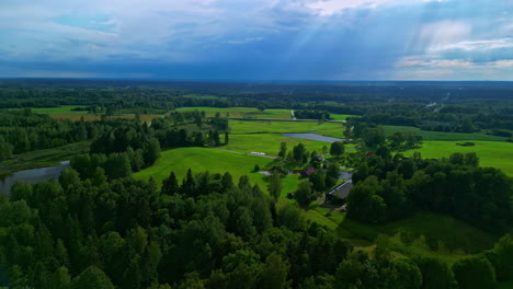Slow-Motion-drone-view-,green-pastures,-rain-and-clouds-in-distance,-god-rays