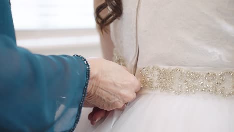 Woman's-Hand-Zipping-Up-Back-of-Bride's-Wedding-Dress