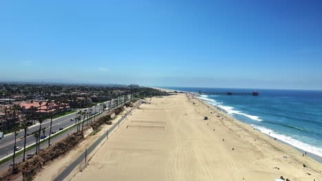 Drohne-Schwenkt-Nach-Links-Den-Strand-Hinunter-Und-Blickt-Auf-Den-Pier-In-Huntington-Beach,-Kalifornien