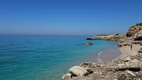 Dreamy-beach-with-untouched-sand-and-cliffs-washed-by-blue-sea,-paradise-summer-vacation-in-Mediterranean,-Albania