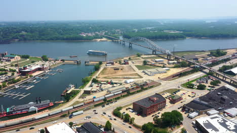 Aerial-view-following-a-riverboat-leaving-the-Dubuque-town-at-the-Mississippi-river,-in-sunny-Iowa,-USA