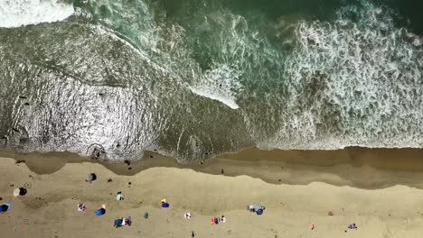 Straight-down-aerial-view-of-the-waves-surf-sand-and-people-on-Huntington-Beach-CA