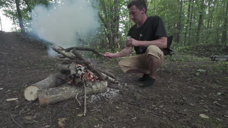 A-man-tending-to-the-campfire-in-the-forest---slow-motion