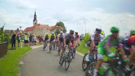 Stunning-HD-footage-of-cyclists-participating-in-a-tour-of-Slovenia,-pedaling-through-Svetinje-and-vineyards,-while-cheerful-children-along-the-road-cheer-them-on