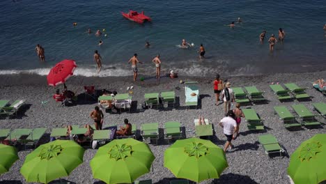 Am-Ruhigen,-Berühmten-Strand-Von-Camogli-In-Der-Region-Ligurien-In-Italien-Nehmen-Menschen-Ein-Sonnenbad-Und-Spielen-Wasseraktivitäten