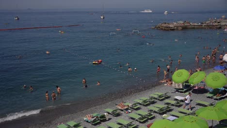Scene-of-tourists-sunbathing-and-enjoying-the-water-fun-along-the-famous-Camogli-Beach,-Italy