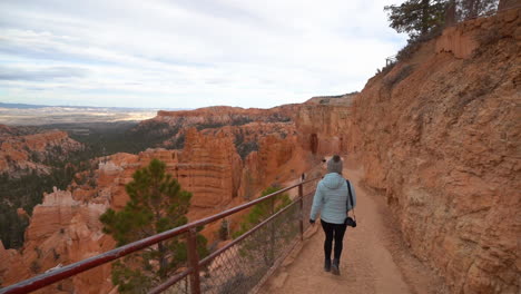 Frau-Geht-Auf-Einem-Wanderweg-Mit-Atemberaubender-Aussicht-Auf-Die-Landschaft-Des-Bryce-Canyon-Nationalparks,-Zeitlupe,-Rückansicht