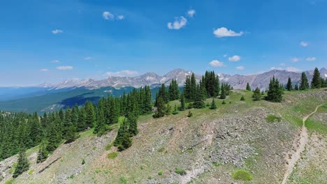 Antena-Sobre-Los-árboles-Y-Colinas-De-Cottonwood-Pass-Con-Las-Montañas-Rocosas-En-El-Fondo,-Colorado,-EE.UU.