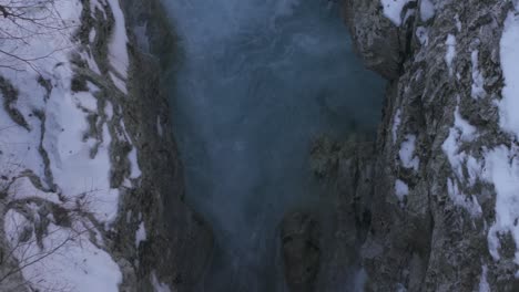 Smaragdgrünes-Wasser-Eines-Gebirgsflusses,-Der-Zwischen-Gefrorenen,-Schneebedeckten-Felsen-Fließt
