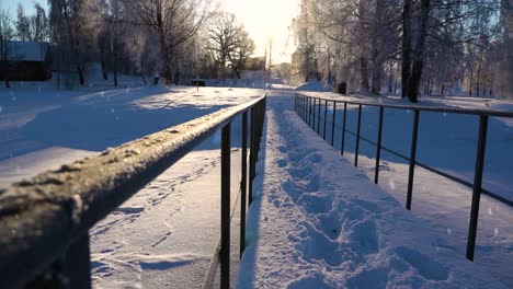 Deep-foot-prints-on-snow-over-steel-old-bridge,-majestic-winter-sunset-and-snowfall