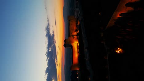 Luftaufnahme-Der-Beleuchteten-Festung-Rocca-Albornoziana-Mit-Sonnenuntergangshimmel-Im-Hintergrund
