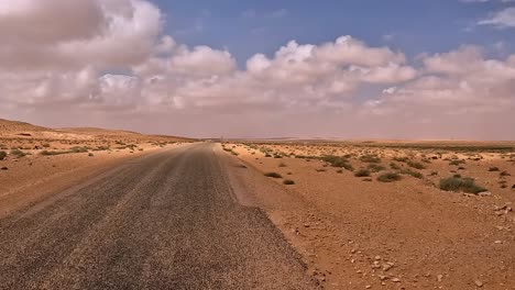 First-person-POV-driving-along-solitary-Tunisia-desert-road,-car-driver-point-of-view