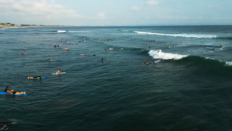 Surfers-waiting-for-waves-at-Batu-Bolong-beach,-Bali,-Indonesia,-aerial-view
