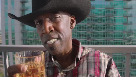 Portrait-shot-of-Black-man-with-cowboy-hat-tipping-shot-glass