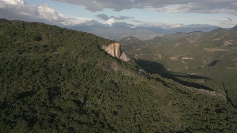 Aerial-orbits-tall-calcite-flowstone-rock-cliff-at-Hierve-el-Agua,-MX
