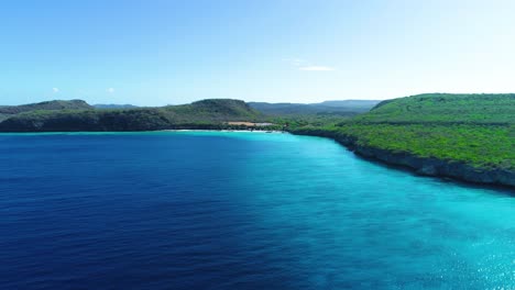 Rising-aerial-drone-above-crystal-clear-deep-blue-caribbean-waters-of-curacao