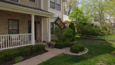 Pull-back-from-a-nice-house-in-the-suburbs-with-a-rainbow-flag-hanging-off-the-front-porch-and-waving-in-the-breeze