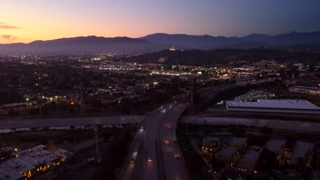 Drone-shot-highway-in-America-at-sunset-with-mountains-in-background
