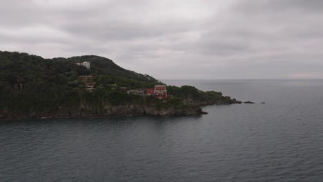 Aerial-forward-to-hotel-resorts-on-a-coastal-cliff,-island-Ischia-in-Italy